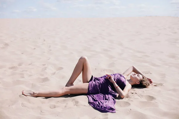 Mladá, štíhlá dívka s purpurovým hadříkem pózuje v poušti — Stock fotografie