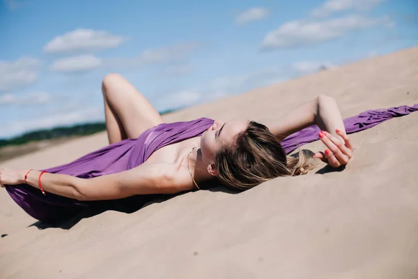 Mladá, štíhlá dívka s purpurovým hadříkem pózuje v poušti — Stock fotografie