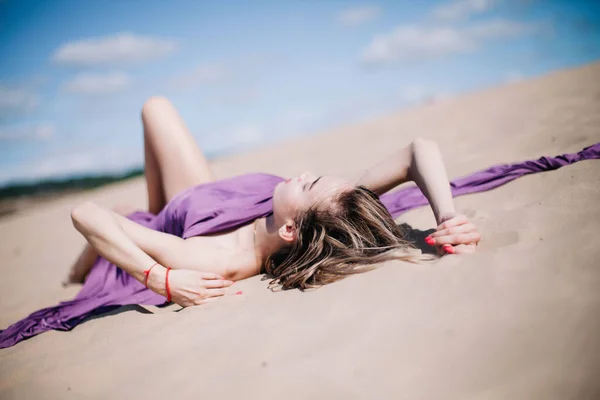 若いです,紫の布のポーズを持つスレンダーな女の子砂漠で — ストック写真