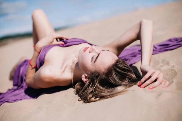 Ung, smal flicka med lila tyg poser i öknen — Stockfoto