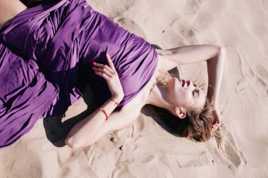 Çölde mor elbiseli genç, narin bir kız poz veriyor.