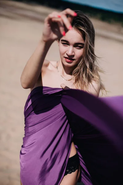 Jeune fille mince avec des poses de tissu violet dans le désert — Photo