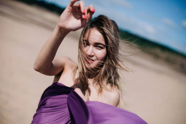 Jeune fille mince avec des poses de tissu violet dans le désert — Photo