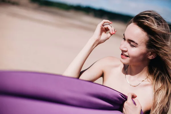 Jeune fille mince avec des poses de tissu violet dans le désert — Photo