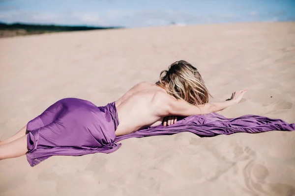 Jeune fille mince avec des poses de tissu violet dans le désert — Photo