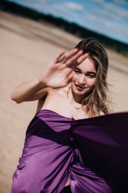 Çölde mor elbiseli genç, narin bir kız poz veriyor.