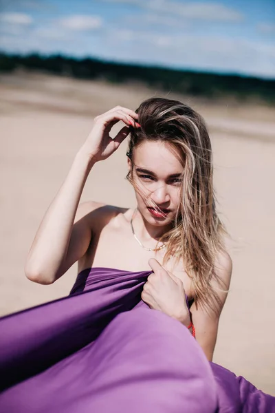 Young, slender girl with purple cloth poses in the desert — Stock Photo, Image