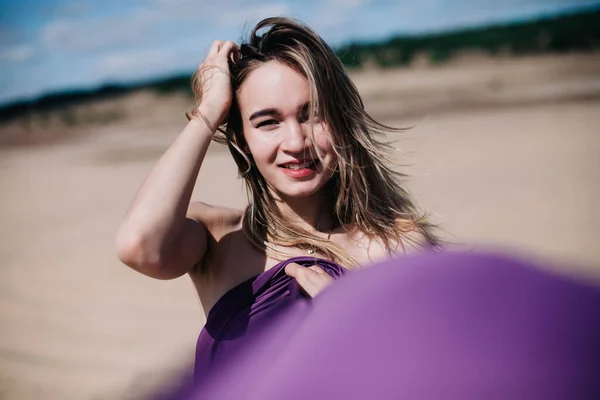 Menina jovem e esbelta com poses de pano roxo no deserto — Fotografia de Stock