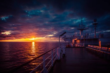 Feribot gün batımında denizin üzerinden geçiyor.