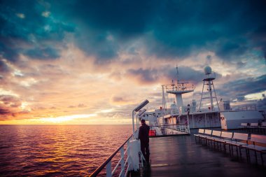 İnsanlar gün batımının güzel gökyüzüne karşı güvertede yürür