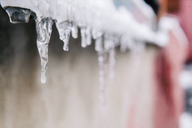 İlk küçük buz saçakları çatıdan sarkıyor ve güneşte eriyor.