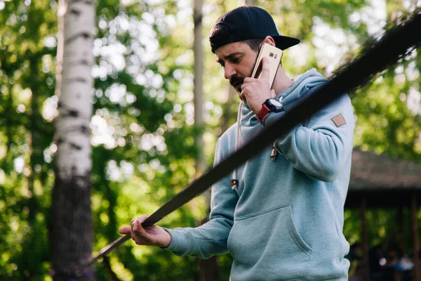 Retrato de um jovem, atlético, barbudo cara em um capuz azul perto de slackline — Fotografia de Stock