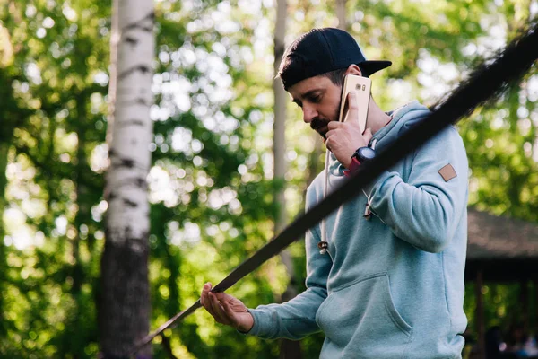 젊고, 운동 선수에 수염을 기른 남자의 사진이 slackline 근처의 파란 후드를 입은 남자 — 스톡 사진