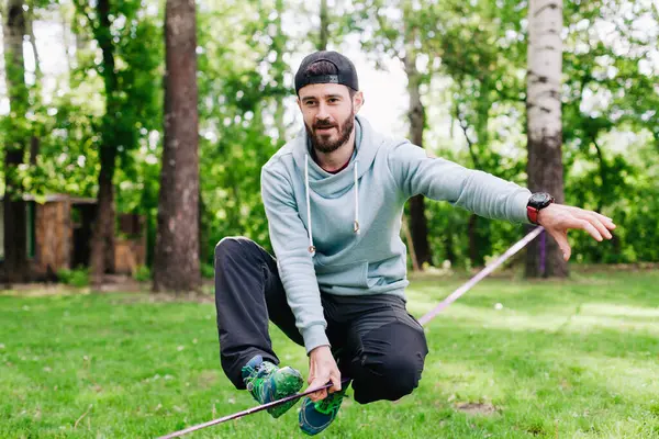 Jovem homem equilibrando e pulando em slackline. — Fotografia de Stock