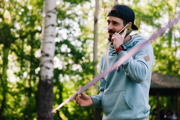 Retrato de um jovem, atlético, barbudo cara em um capuz azul perto de slackline — Fotografia de Stock