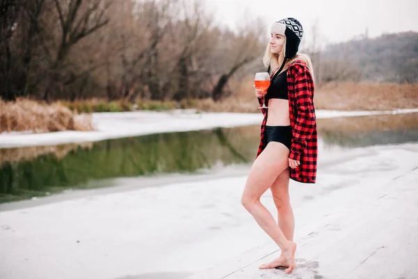 Egy fürdőruhás lány és egy üveggel a kezében pózol télen a hidegben. — Stock Fotó