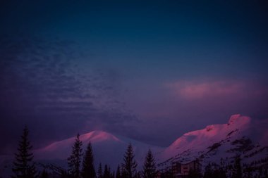 Şafak vakti güneşin ilk ışıkları dağların karla kaplı zirvelerine dokunur.