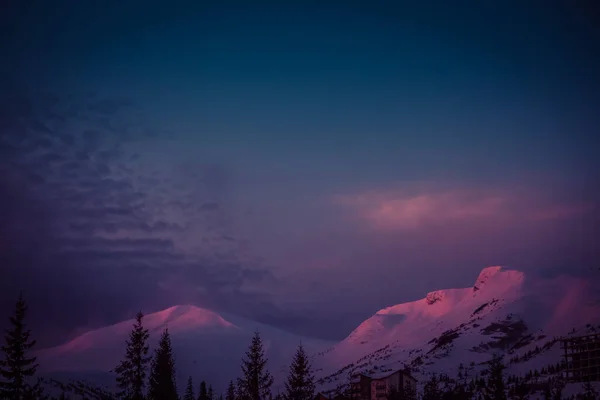 De eerste zonnestralen bij zonsopgang raken de besneeuwde toppen van de bergen — Stockfoto
