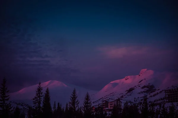 Los primeros rayos del sol al amanecer tocan los picos nevados de las montañas — Foto de Stock