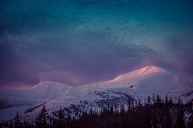 Şafak vakti güneşin ilk ışıkları dağların karla kaplı zirvelerine dokunur.