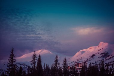 Şafak vakti güneşin ilk ışıkları dağların karla kaplı zirvelerine dokunur.