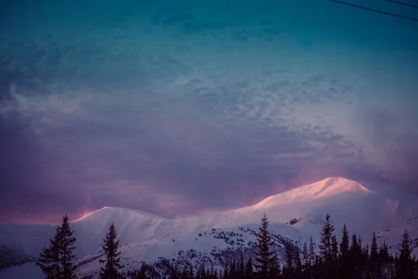 Los primeros rayos del sol al amanecer tocan los picos nevados de las montañas — Foto de Stock