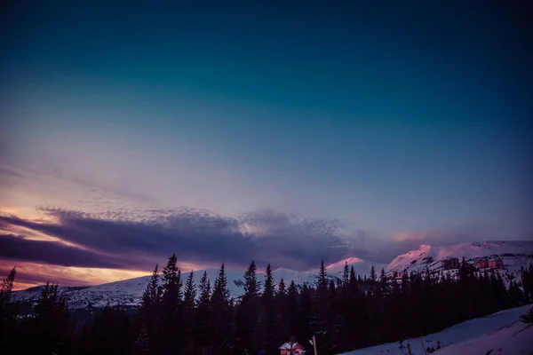 Los primeros rayos del sol al amanecer tocan los picos nevados de las montañas — Foto de Stock