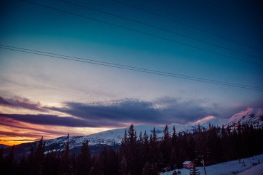 Şafak vakti güneşin ilk ışıkları dağların karla kaplı zirvelerine dokunur.