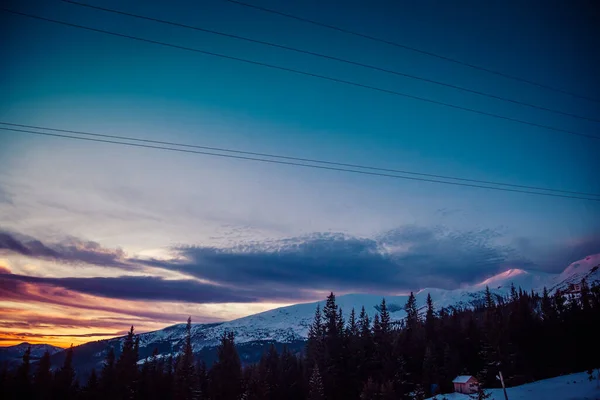 Los primeros rayos del sol al amanecer tocan los picos nevados de las montañas — Foto de Stock