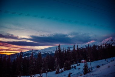 Şafak vakti güneşin ilk ışıkları dağların karla kaplı zirvelerine dokunur.
