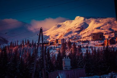 Şafak vakti güneşin ilk ışıkları dağların karla kaplı zirvelerine dokunur.