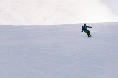 Adam parlak bir takım elbiseyle yamaçtan kayıyor.