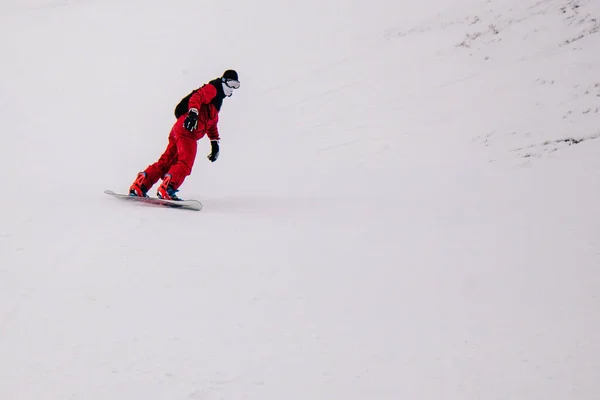 Guy en combinaison rouge vif monte freeride sur un snowboard — Photo