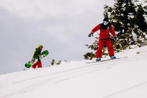 Kerl im knallroten Jumpsuit fährt Freeride auf einem Snowboard — Stockfoto