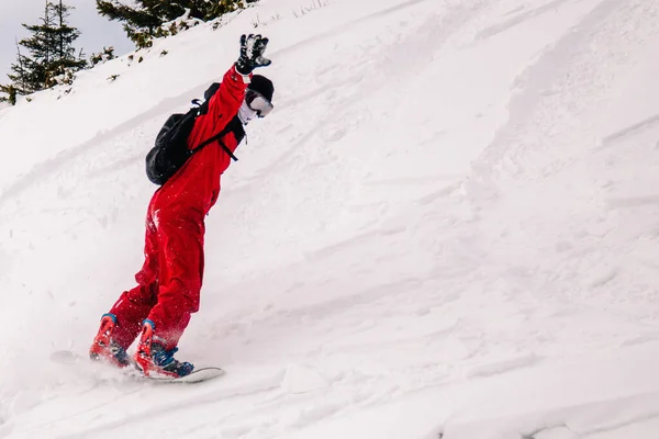 Cara de macacão vermelho brilhante monta freeride em um snowboard — Fotografia de Stock