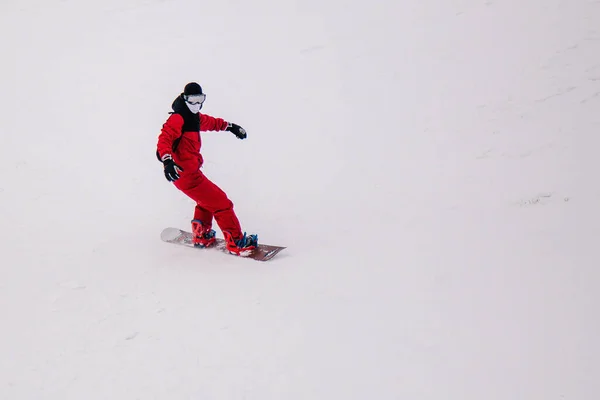 Chlap v jasně červené kombinéze jezdí freeride na snowboardu — Stock fotografie
