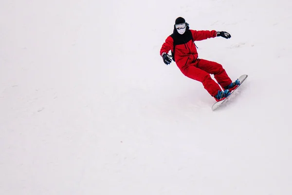 Facet w jasnoczerwonym kombinezonie jeździ freeride na snowboardzie — Zdjęcie stockowe