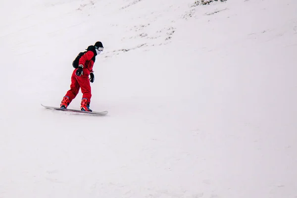 Guy en combinaison rouge vif monte freeride sur un snowboard — Photo