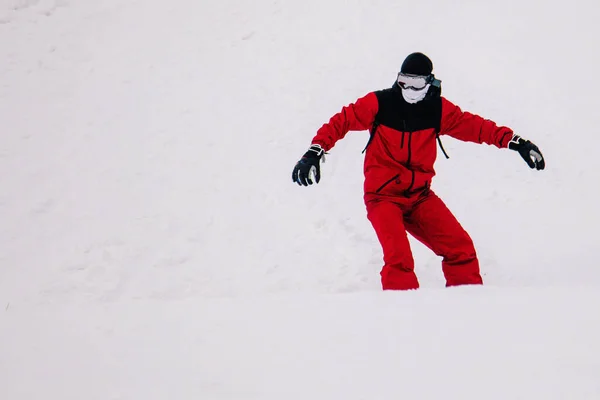Chlap v jasně červené kombinéze jezdí freeride na snowboardu — Stock fotografie