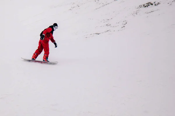 Ragazzo in tuta rossa brillante cavalca freeride su uno snowboard — Foto Stock