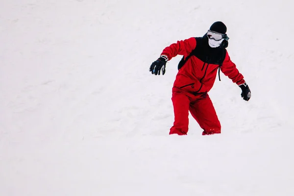 Guy in bright red jumpsuit rides freeride on a snowboard — Stock Photo, Image