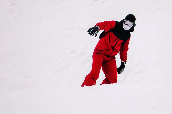 Ragazzo in tuta rossa brillante cavalca freeride su uno snowboard — Foto Stock