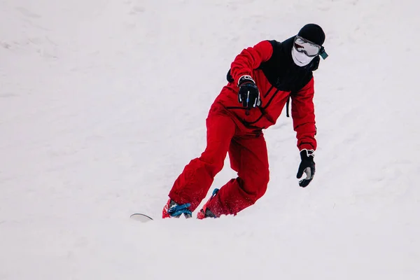 Cara de macacão vermelho brilhante monta freeride em um snowboard — Fotografia de Stock