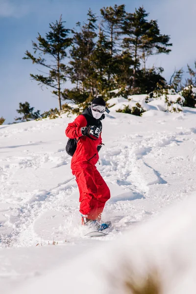 Guy scivola lungo il pendio su uno snowboard con una tuta rossa — Foto Stock