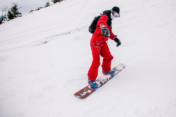 Cara de macacão vermelho brilhante monta freeride em um snowboard — Fotografia de Stock