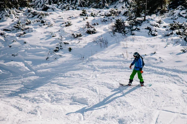 Ragazzo in tuta brillante cavalca freeride su uno snowboard — Foto Stock