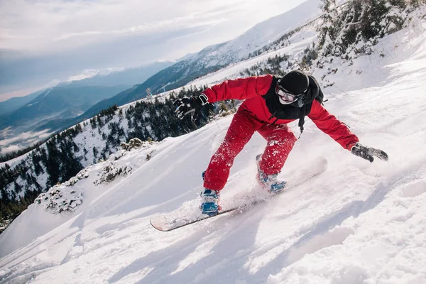 Kerl im knallroten Jumpsuit fährt Freeride auf einem Snowboard — Stockfoto
