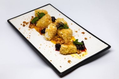 Izgara peynir, beyaz bir tabakta otlar ve sosla birlikte.