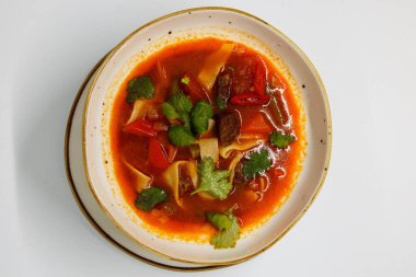 Beyaz arka planda, derin tabakta baharatlı çorba.