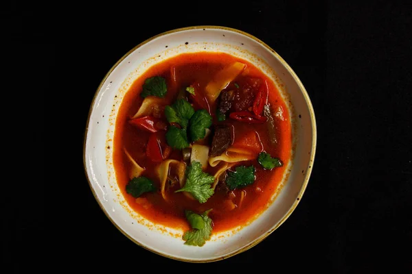 Sopa picante em uma placa profunda em um fundo preto — Fotografia de Stock